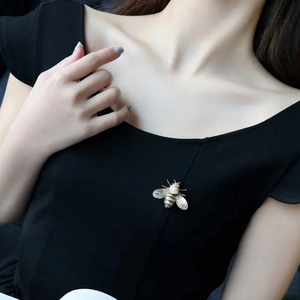 Detailed view of elegant bee brooch with pearl on black fabric for a luxury look
