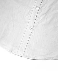 Macro detail of textured linen-cotton fabric and white resin buttons on the shirt hem