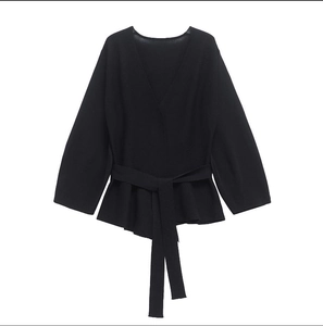 Close-up of black V-neck knit sweater with wrap waist tie and peplum hem detail