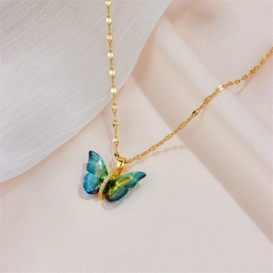 Detailed close-up of a blue-green gradient butterfly pendant on a gold chain necklace