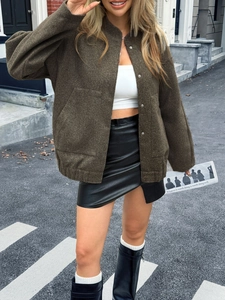 Street style view of a dark green textured jacket with snap buttons and a mini skirt