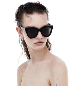 Close-up of black thick-frame cat-eye sunglasses on a model with wet hair look