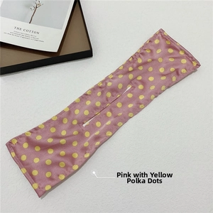 Detail view of pink hair bun maker with yellow polka dots on a white textured background