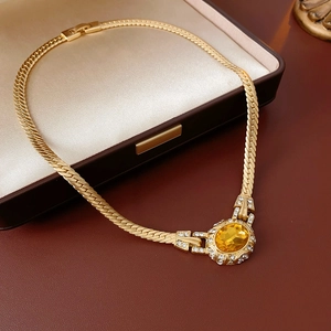 Detail of vintage gold snake chain necklace with an oval yellow gemstone and rhinestones