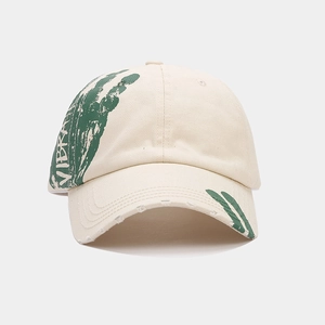 Detail of cream cotton baseball cap featuring green art print and distressed edges