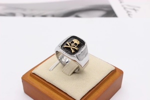 Macro shot of silver punk skull ring with golden bone relief on a jewelry display stand