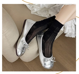 Detail of silver ballet flats with bow and black openwork bow patterned crew socks