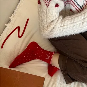 Detail of red crew socks with white polka dots, ruffle trim, and delicate bow accents