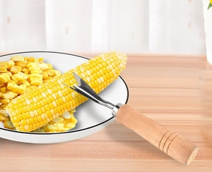 Macro shot of stainless steel V-blade corn peeler with wooden handle removing fresh kernels