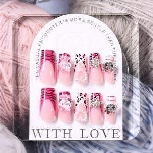 Detail of pink gradient press-on nails with 3D pearls, hearts and cat bow ornaments