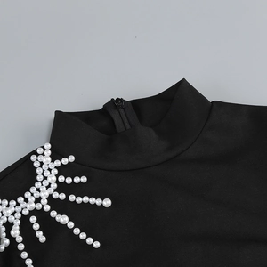 Détail de robe noire à col montant avec fermeture éclair et ornements de perles