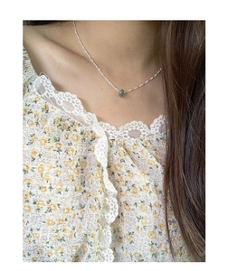 Close-up of S925 sterling silver chain with a green jade bead pendant on a female neck