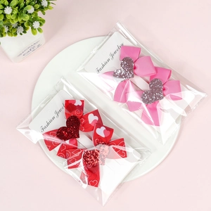 Detail of two-piece heart bow hair clip sets in pink and red on a white ceramic plate