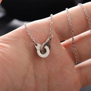 Macro shot of silver handcuff necklace pendant held by hand showing fine details