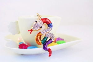 Close-up of rainbow crystal snake pendant with sparkling rhinestones and gold base