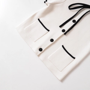 Women's chic contrast trim knit top with black bow and buttons on white background