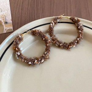 Créoles marron en laine texturée avec détails dorés posées sur une assiette