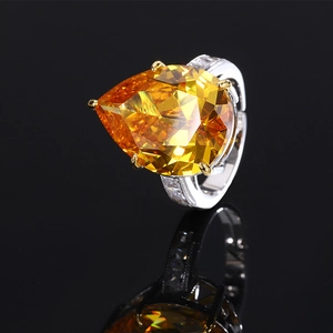 Pear cut yellow gemstone ring with pavé diamonds on a silver band shown on black mirror