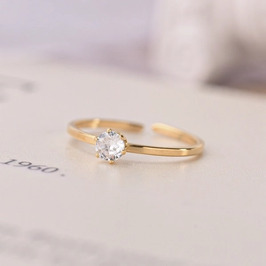 Primo piano di un elegante anello aperto dorato con una brillante pietra di zirconia cubica rotonda