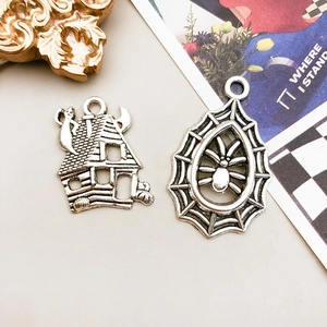 Detail of vintage silver Halloween pendants featuring a haunted house and spider web design