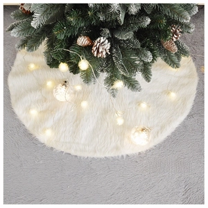 Close-up of white faux fur Christmas tree skirt with soft texture and warm LED lights