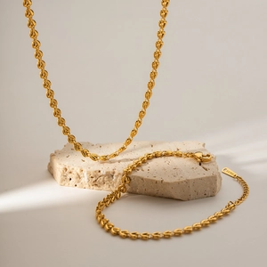 18k gold plated stainless steel woven heart bracelet and necklace set on stone