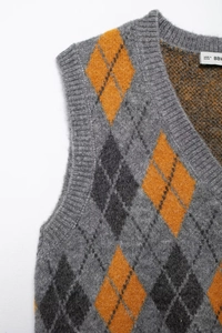 Close-up of knit texture and gray argyle pattern with orange diamond on the shoulder