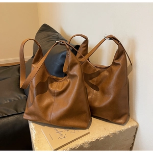 Detail of soft caramel leather texture on minimalist large hobo shoulder bag for women