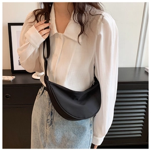 Fashionable black nylon half-moon crossbody bag shown on a model in a minimalist room