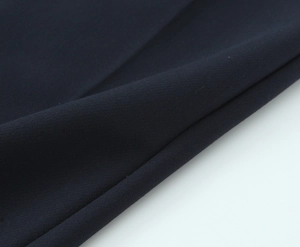 Macro detail of high-quality navy blue crepe fabric showing smooth woven texture and drape