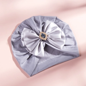 Close-up of baby turban hat with a large satin bow and sparkling rhinestone centerpiece