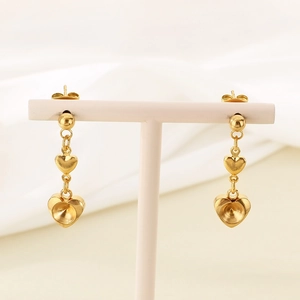 Detailed view of gold-plated stainless steel triple heart dangle earrings on a stand