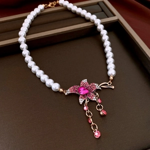 Detail of floral pearl necklace with pink rhinestone flower and tassel on brown tray