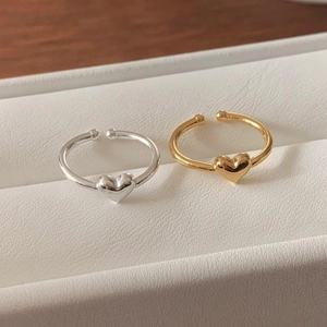 Close-up of minimalist silver and gold heart-shaped open rings in a white jewelry box