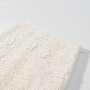 Macro detail of intricate floral lace embroidery and hidden zipper on cream skirt set