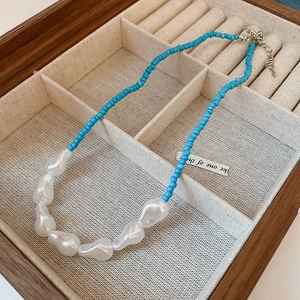 Detailed view of bohemian blue seed beads and baroque pearl necklace in a wooden box