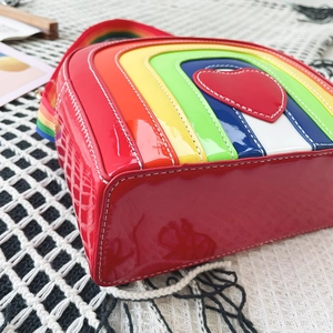 Detail view of the colorful rainbow stitching and heart applique on a red crossbody bag