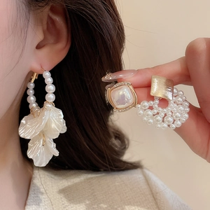 Detailed macro shot of vintage pearl earrings with gold metal and white resin flower petals