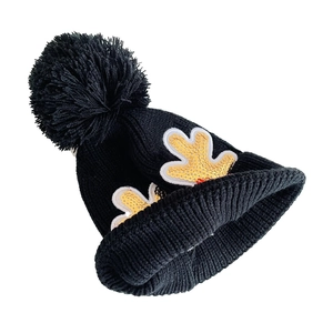 Knitted winter hat in black featuring gold sequin reindeer antlers and a fluffy pom-pom