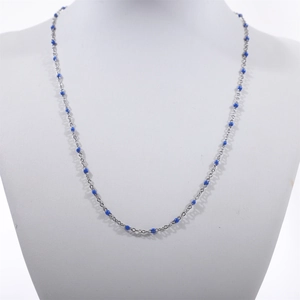 Detail of silver bead chain necklace with dark blue enamel beads on a neck mannequin