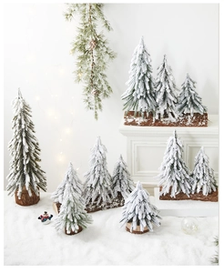 Detailed view of mini snow-flocked Christmas trees with natural wood bases for winter decor