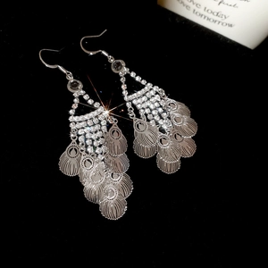 Macro shot of silver leaf tassel earrings with sparkling rhinestones on black velvet