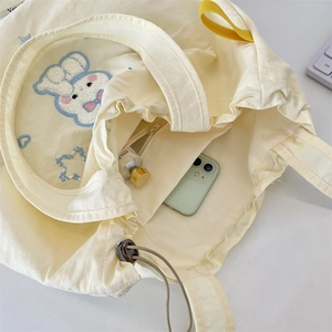Detailed interior of yellow drawstring tote bag with fine rabbit embroidery and zip pocket