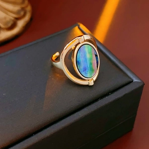 Close-up of golden oval ring featuring iridescent shell stone and elegant metal band