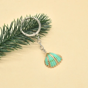 Detailed close-up of a mint green shell keychain with gold edges and silver chain
