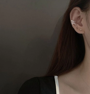 Detail of silver snake-shaped ear cuff with brushed metal texture on a female model