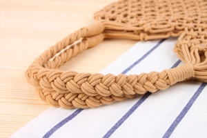 Detail of woven khaki shoulder bag showing braided handles and textured mesh knit pattern