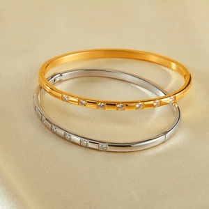Minimalist stainless steel bangles with sparkling cubic zirconia on champagne silk fabric