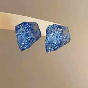 Close-up of blue resin irregular earrings with ice texture and translucent finish