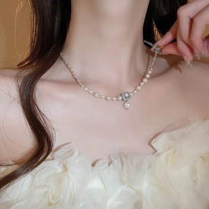 Detail of elegant gold-plated pearl necklace with square gemstone pendant on collarbone
